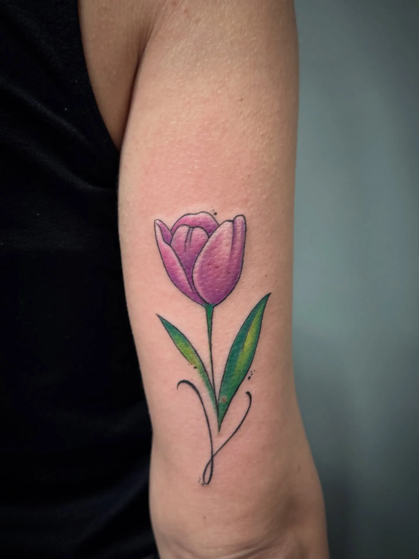 Tatuaggio a colori di un tulipano rosa sul braccio
